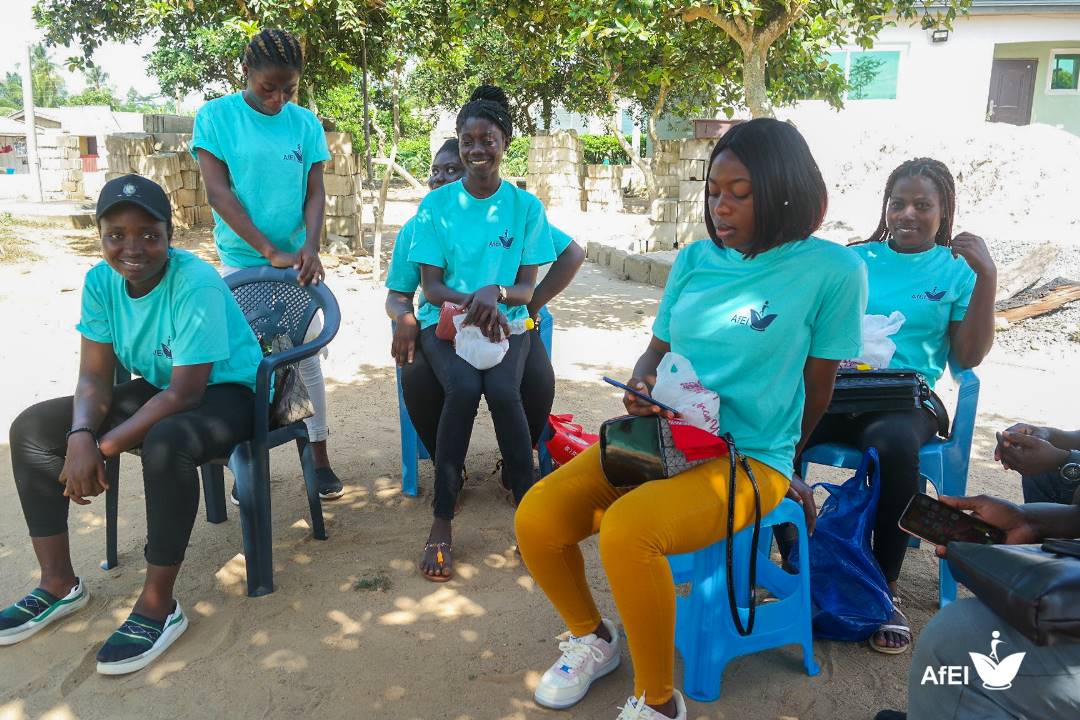Team members in teal T-shirts seated together on chairs outdoors, image 7 of 12
