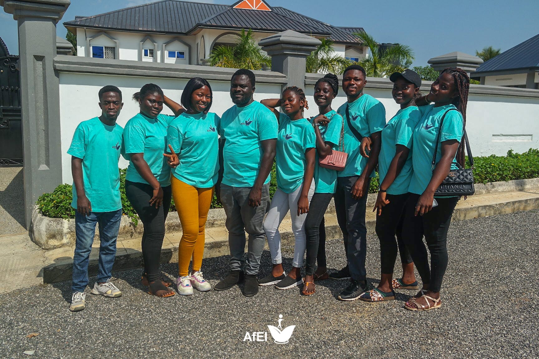 A group of people in teal T-shirts standing together in front of a wall, image 12 of 14
